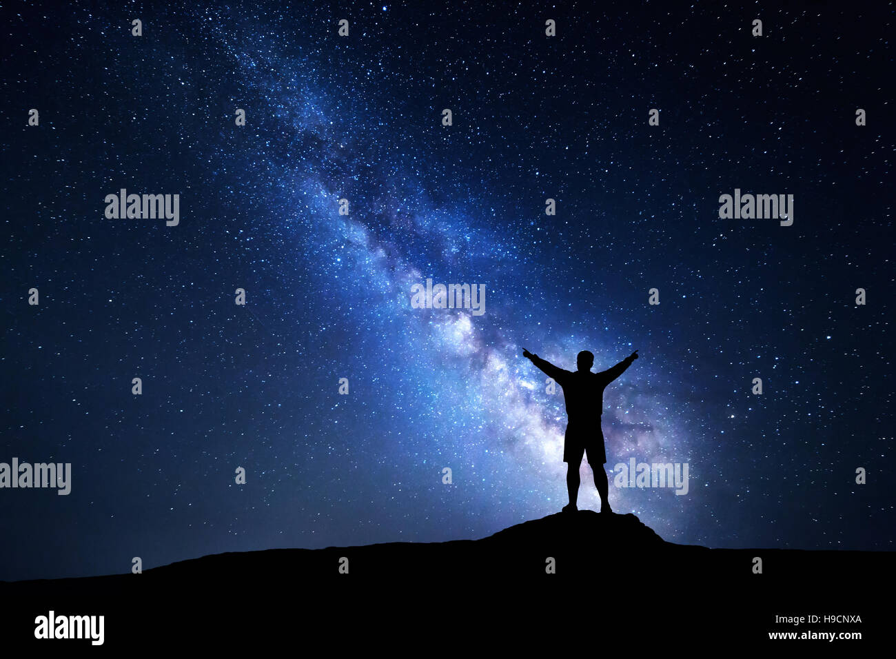 Milky Way with silhouette of a standing happy man with raised up arms ...