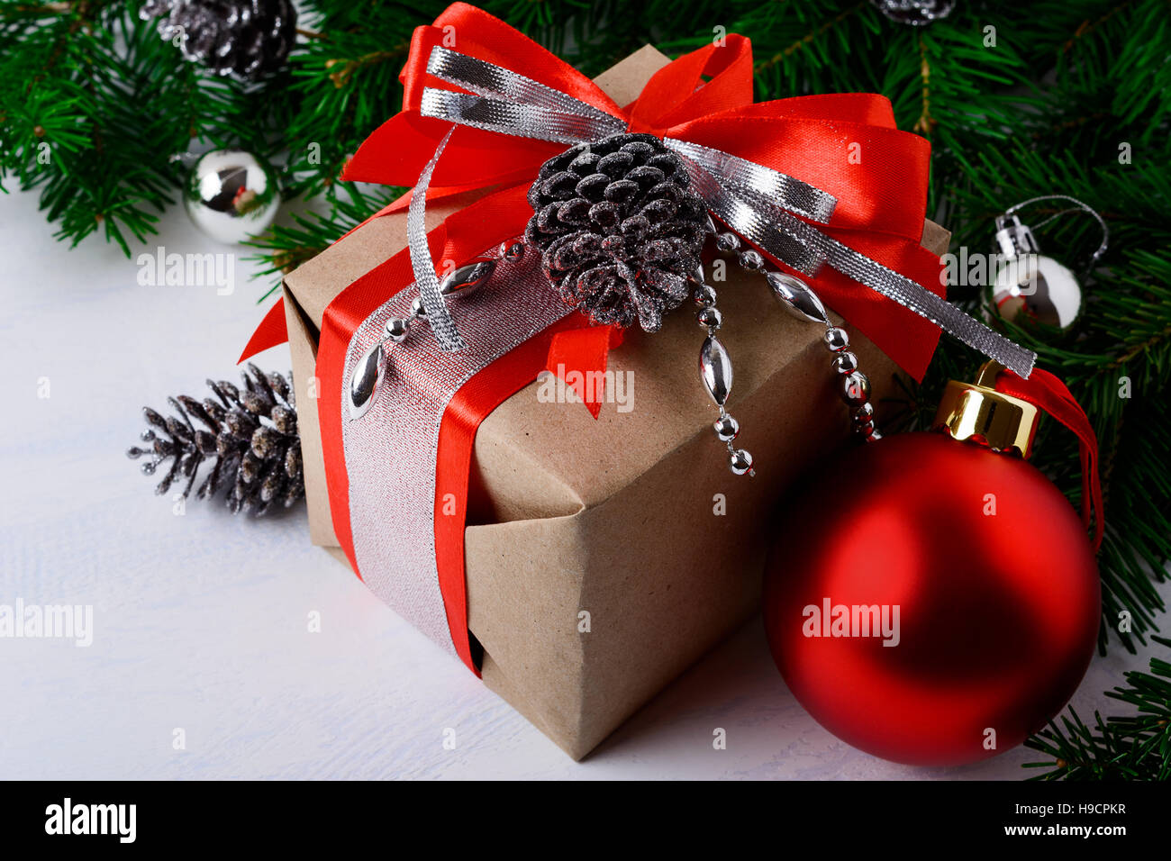 Christmas decorated gift box with red ribbon. Christmas greeting background with red ornament. Stock Photo