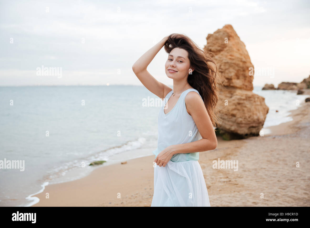 Happy attractive young woman in white dress standing on the beach Stock ...