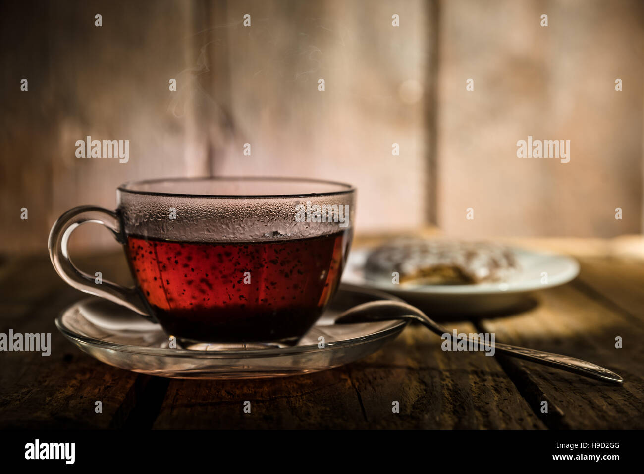 Glass cup of black tea, teaspoon and honey cake on wooden table Stock Photo