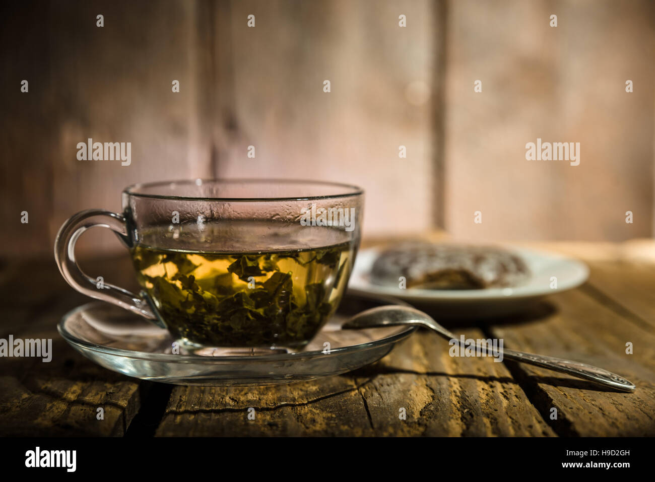 Glass cup of green tea, teaspoon and honey cake on wooden table Stock Photo