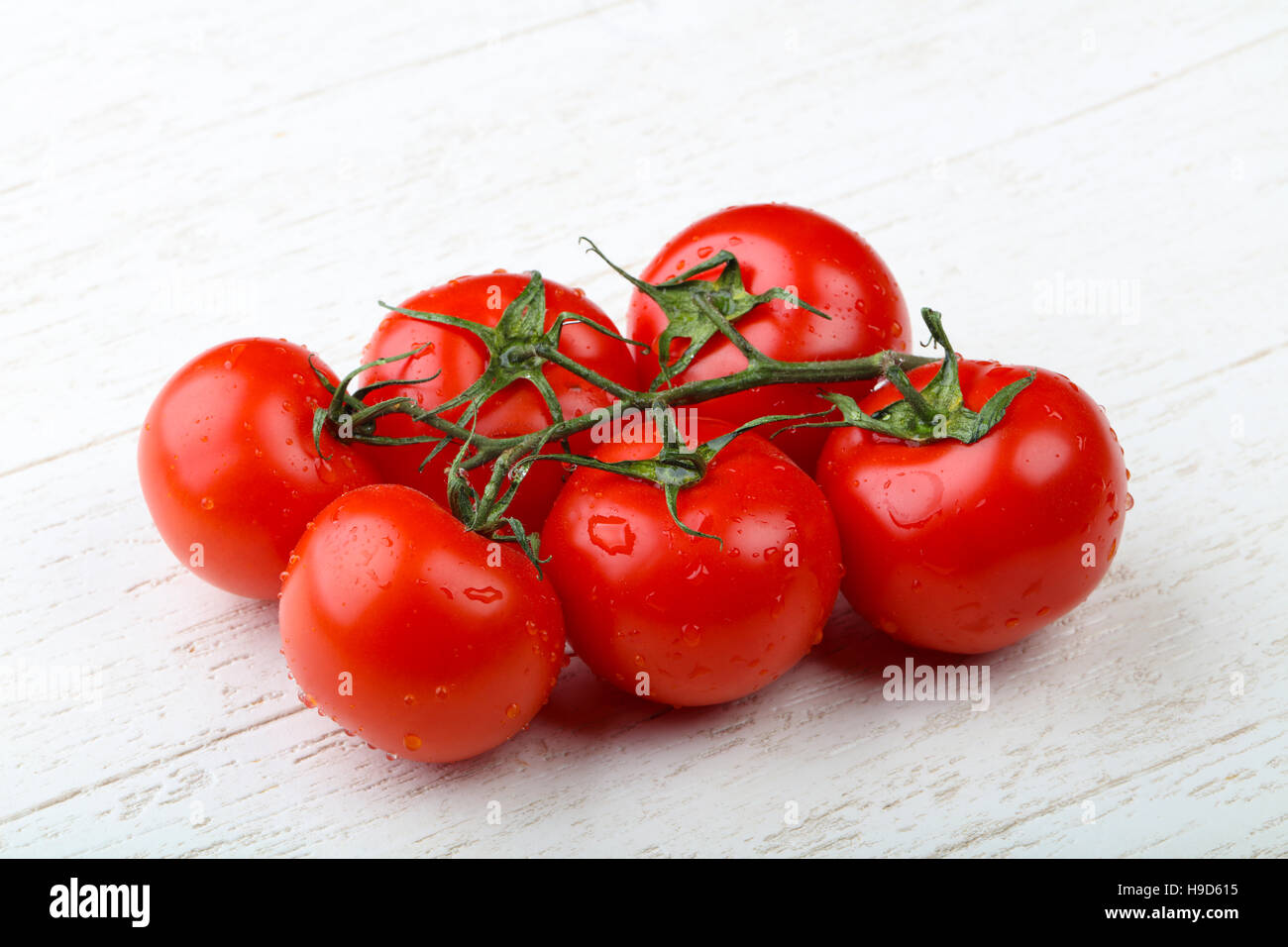 Red tomato branch on the wood background Stock Photo - Alamy