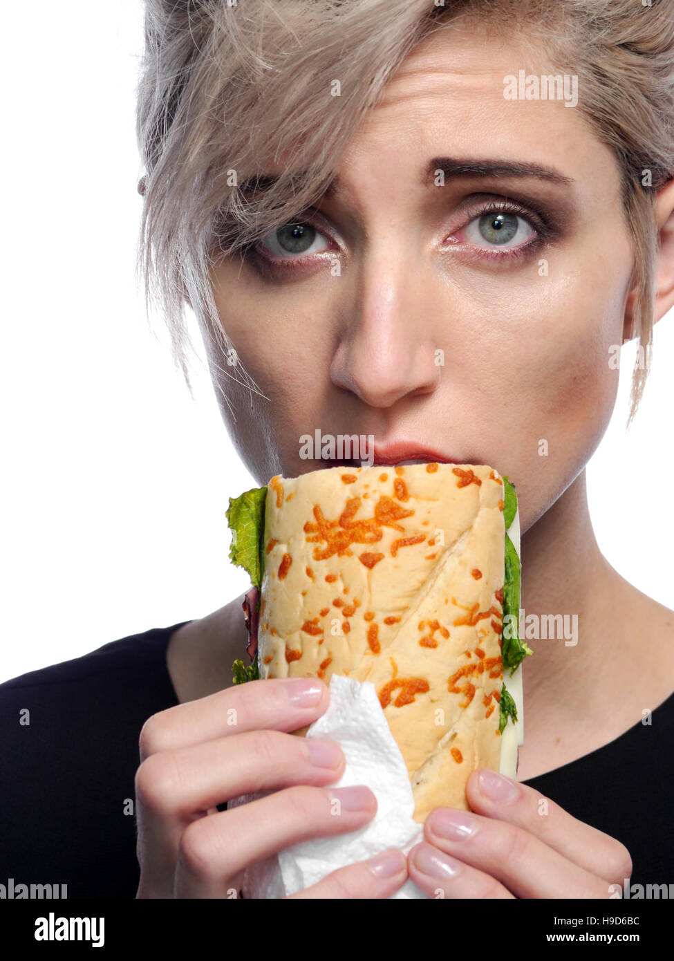 A attractive blonde woman is eating a deli style sandwich Stock Photo