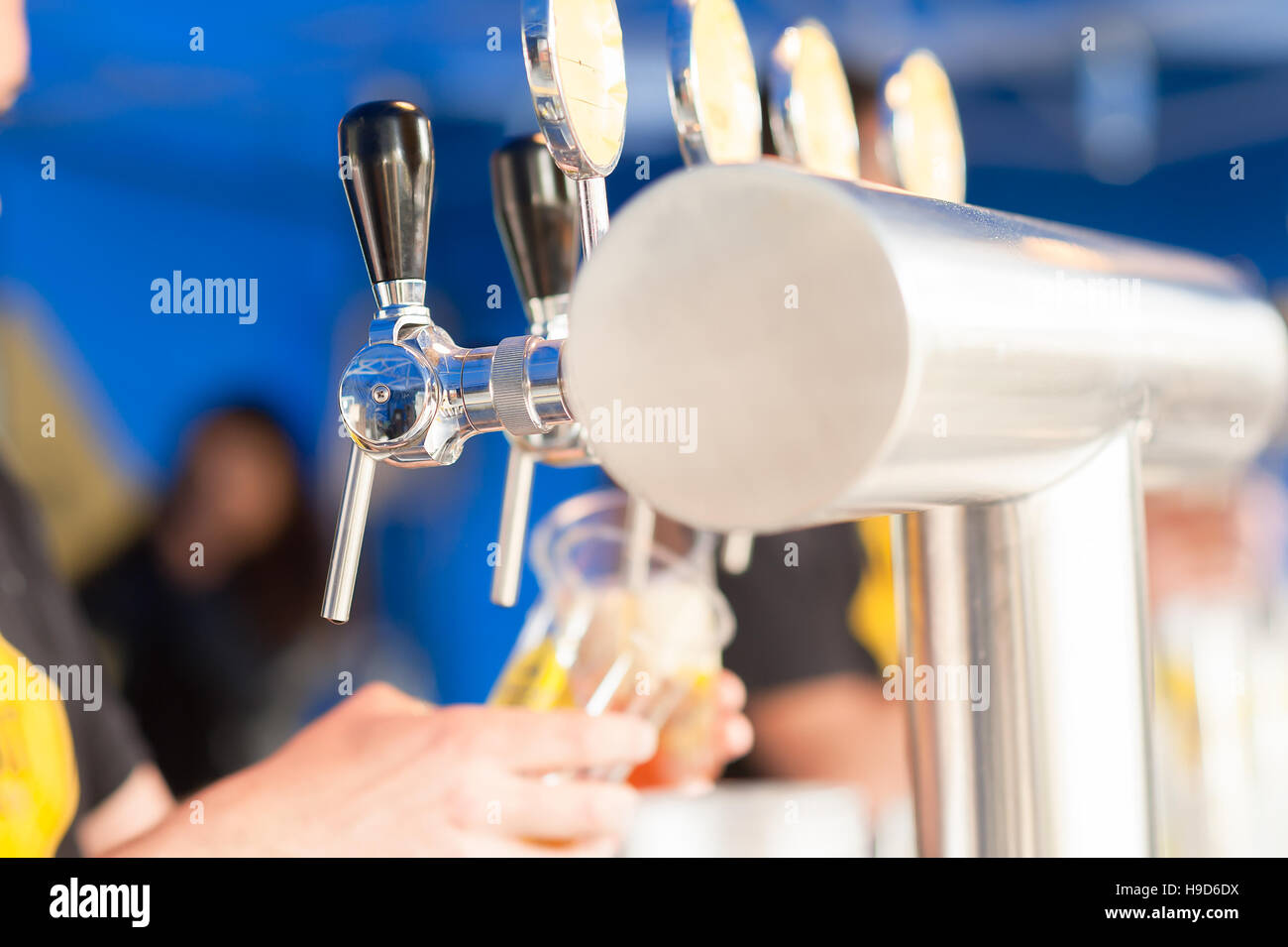 Barman hand at beer tap pouring a drought lager beer serving in a restaurant or pub. Stock Photo