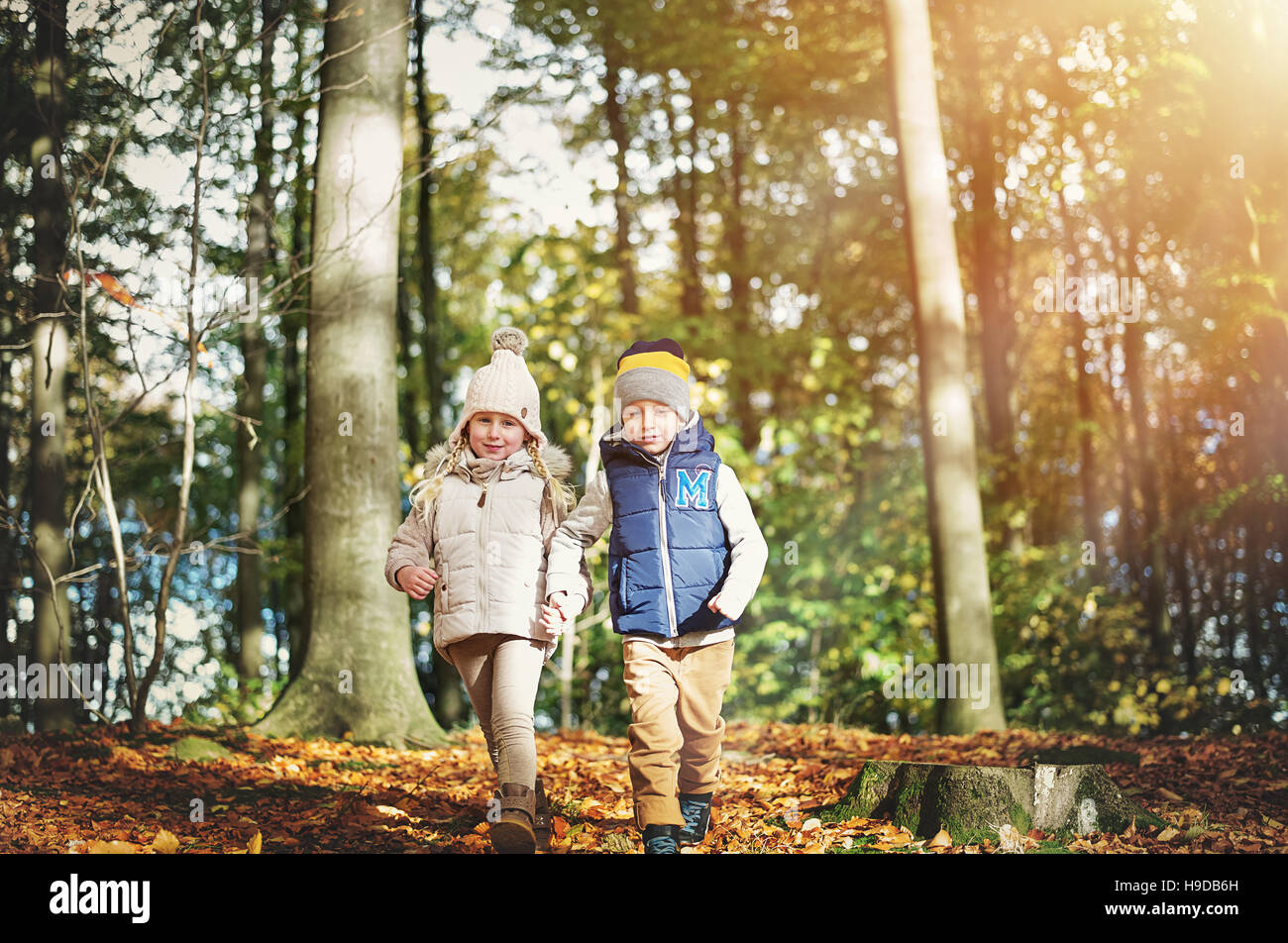 A pair of happy kids in autumn forest. Horizontal outdoors shot Stock Photo