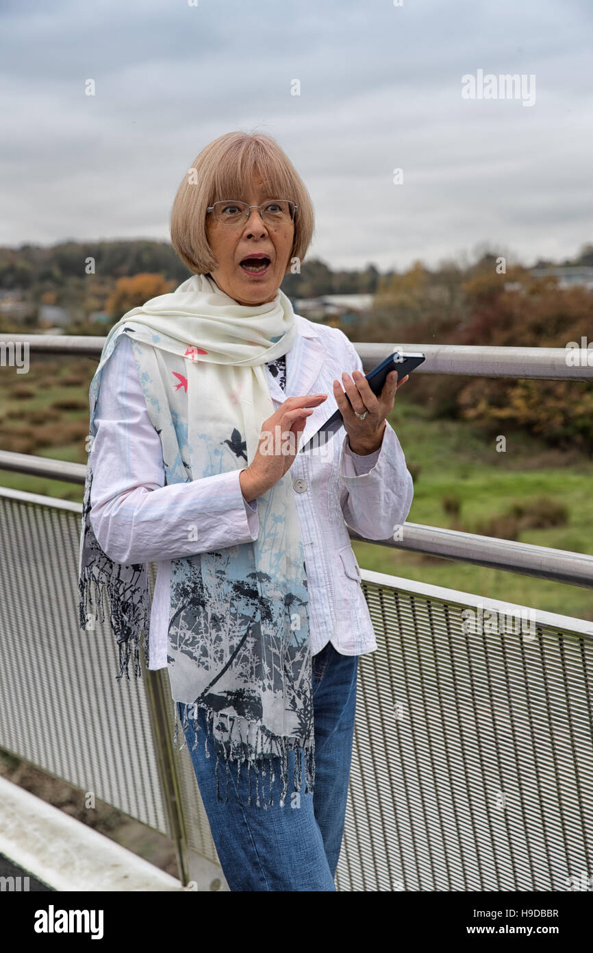 Elderly Japanese woman recieves a shocking text message on her smart phone Stock Photo