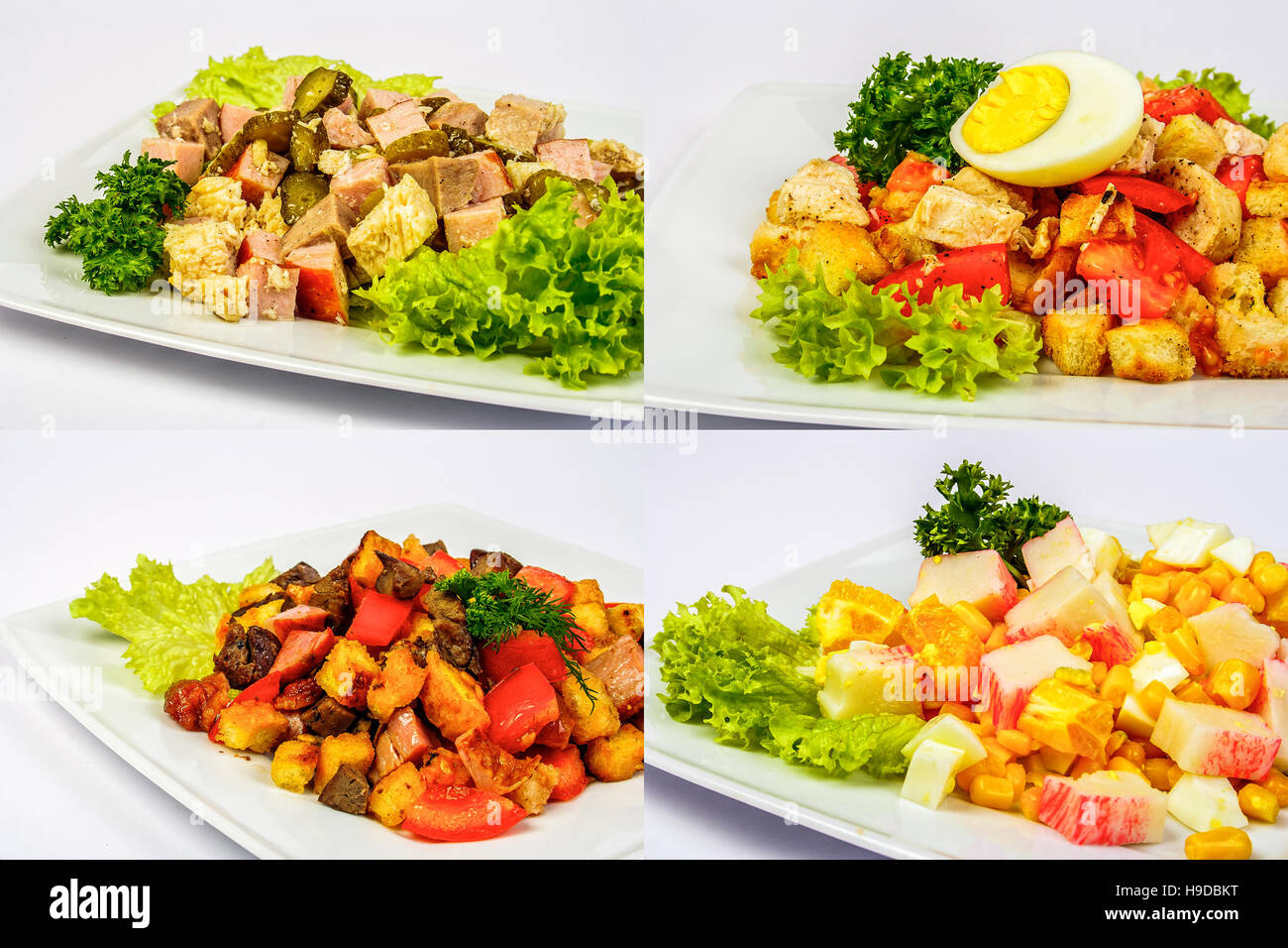 four salads with meat, tomatoes crab sticks, crackers, cucumbers, corn and egg on white plate for celebration table Stock Photo