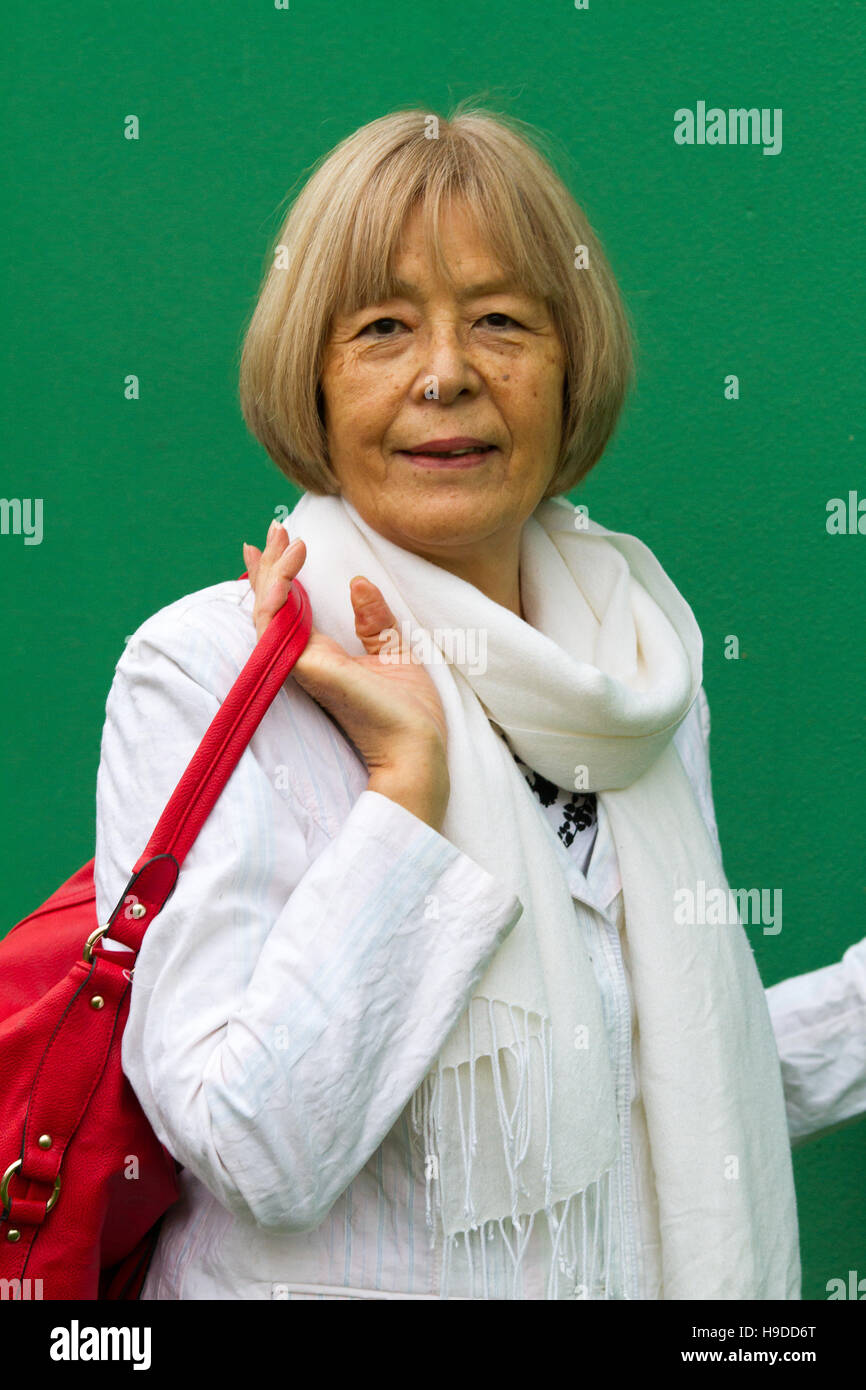 Senior Japanese lady poses in trendy white coat with red shoulder bag Stock Photo