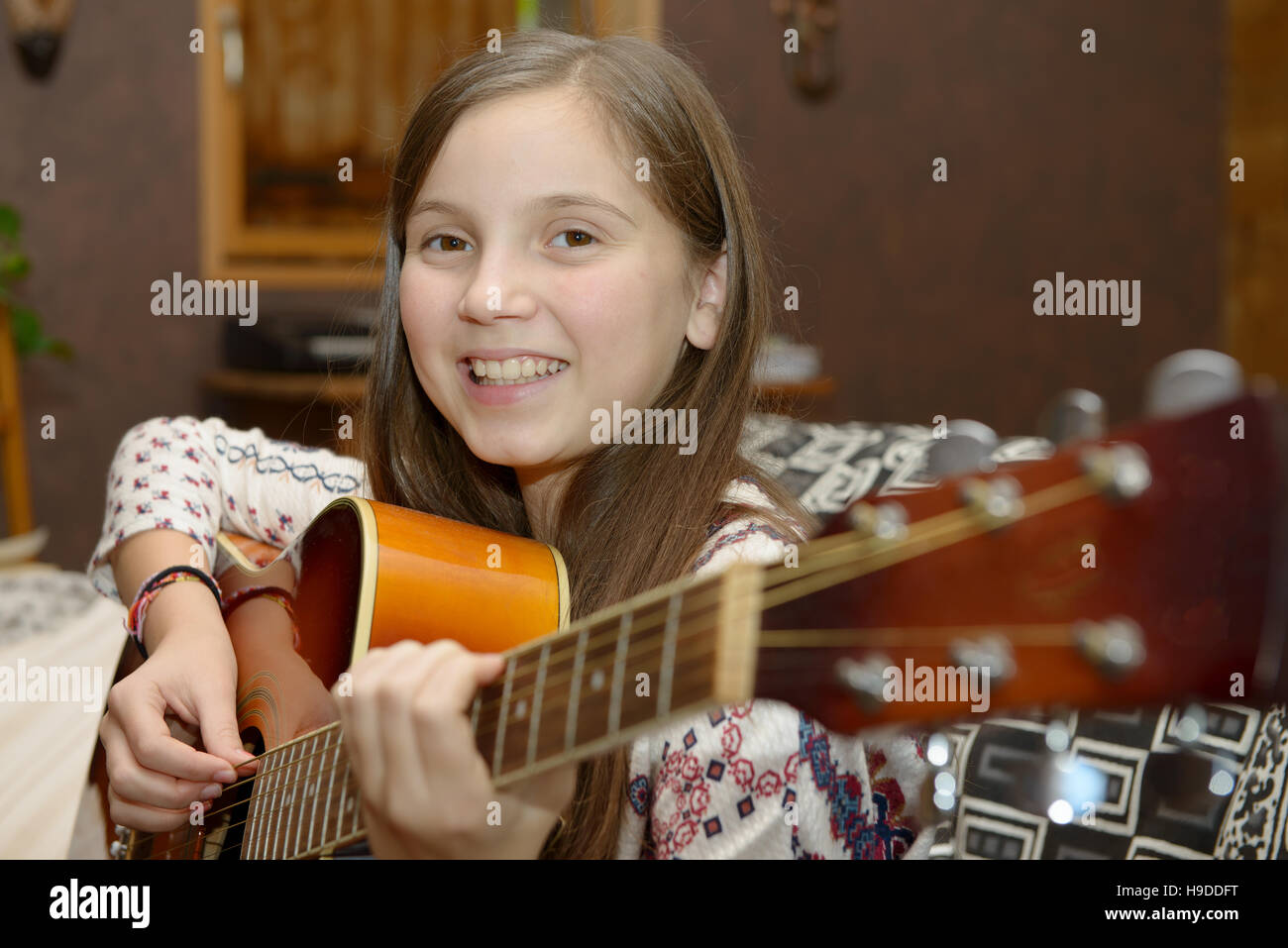 Young teen girl playing acoustic guitar on sofa Stock Photo - Alamy