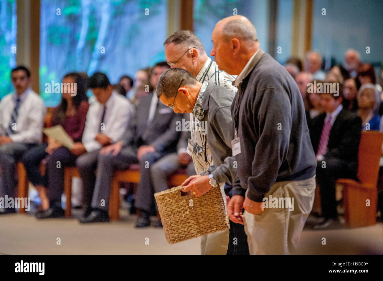 Elderly acolytes at a Catholic Church in Laguna Niguel, CA, bow as they bring filled collection baskets to a priest at the end of a mass. Stock Photo