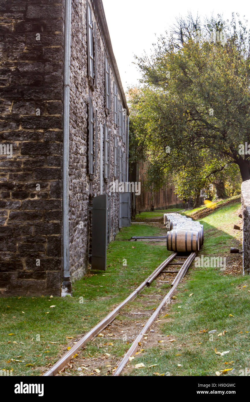 Oak barrels on rails outside stone bourbon distillery. Stock Photo