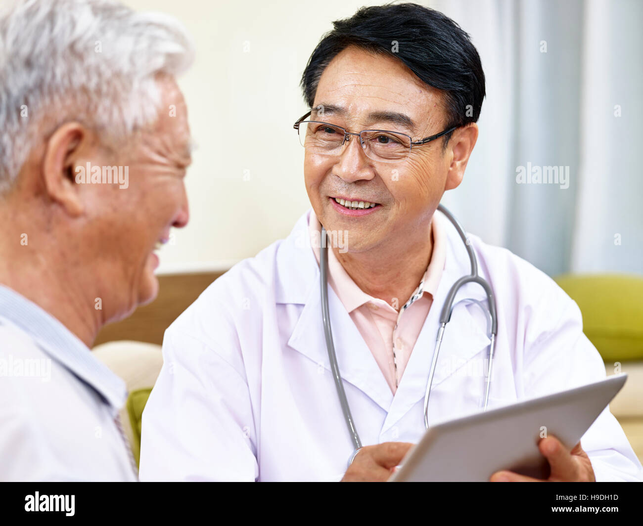 asian doctor talking to a senior patient, happy and smiling Stock Photo