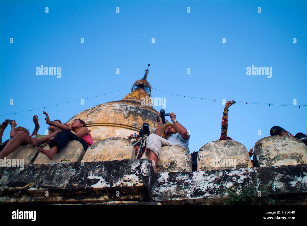 Tourists watch the sun set from the top of a temple in Bagan, an ancient cluster of temples and pagodas in Myanmar (Burma). Stock Photo