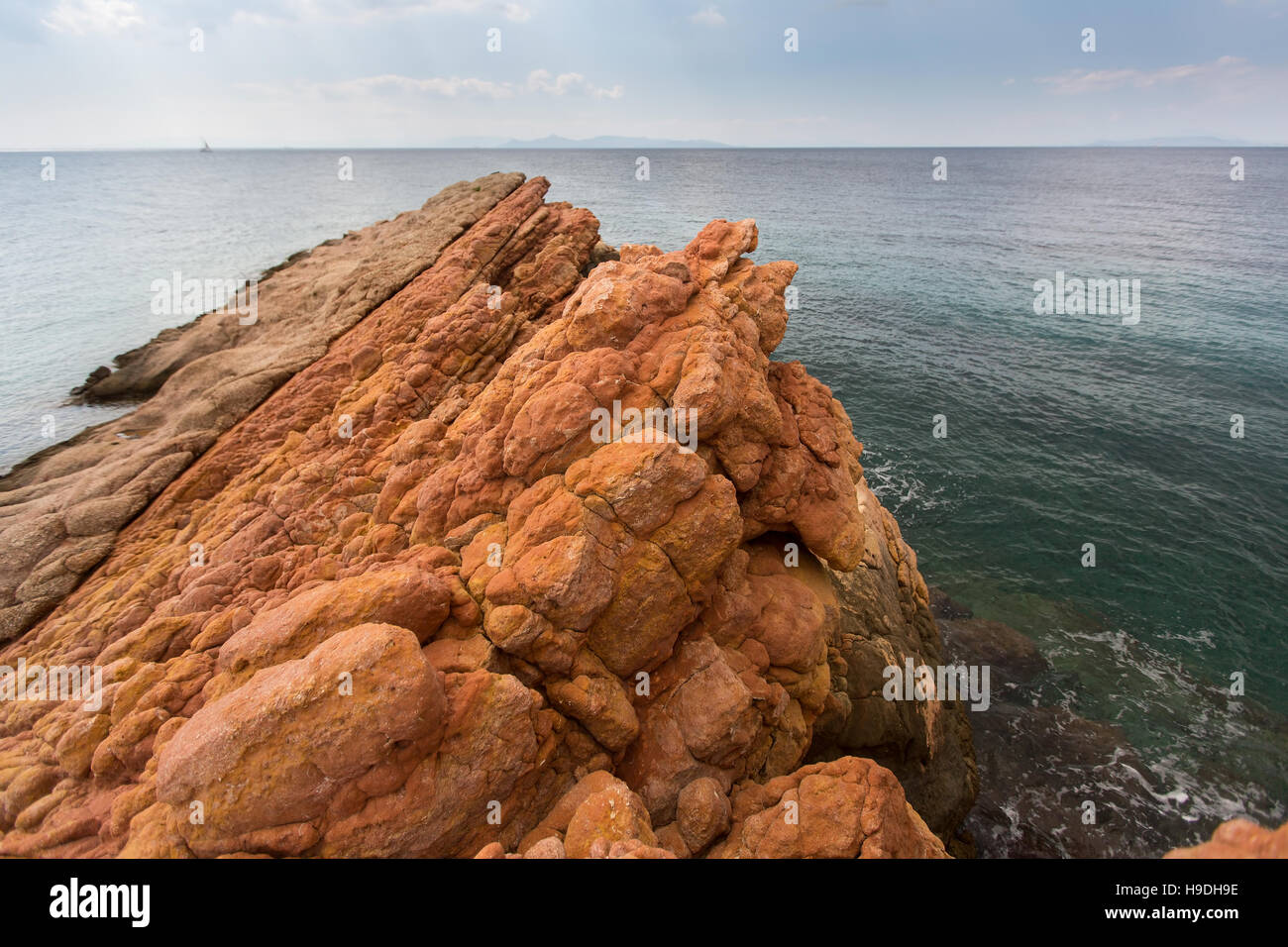 Rocky shore by minerals of the red color, the Aegean sea, near Athens
