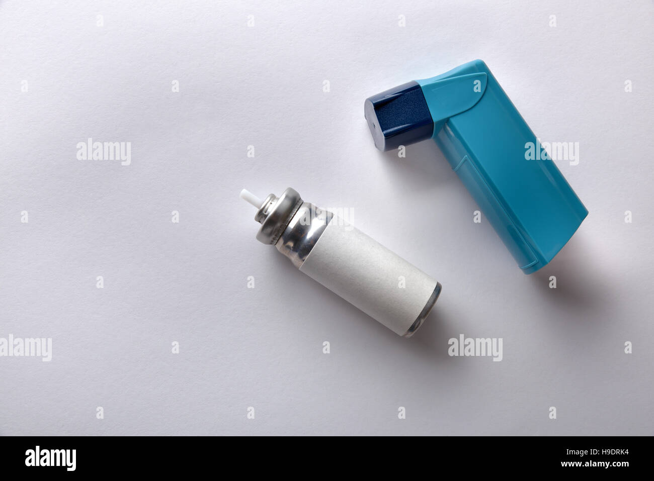Cartridge and blue medicine inhaler on white table. Top view
