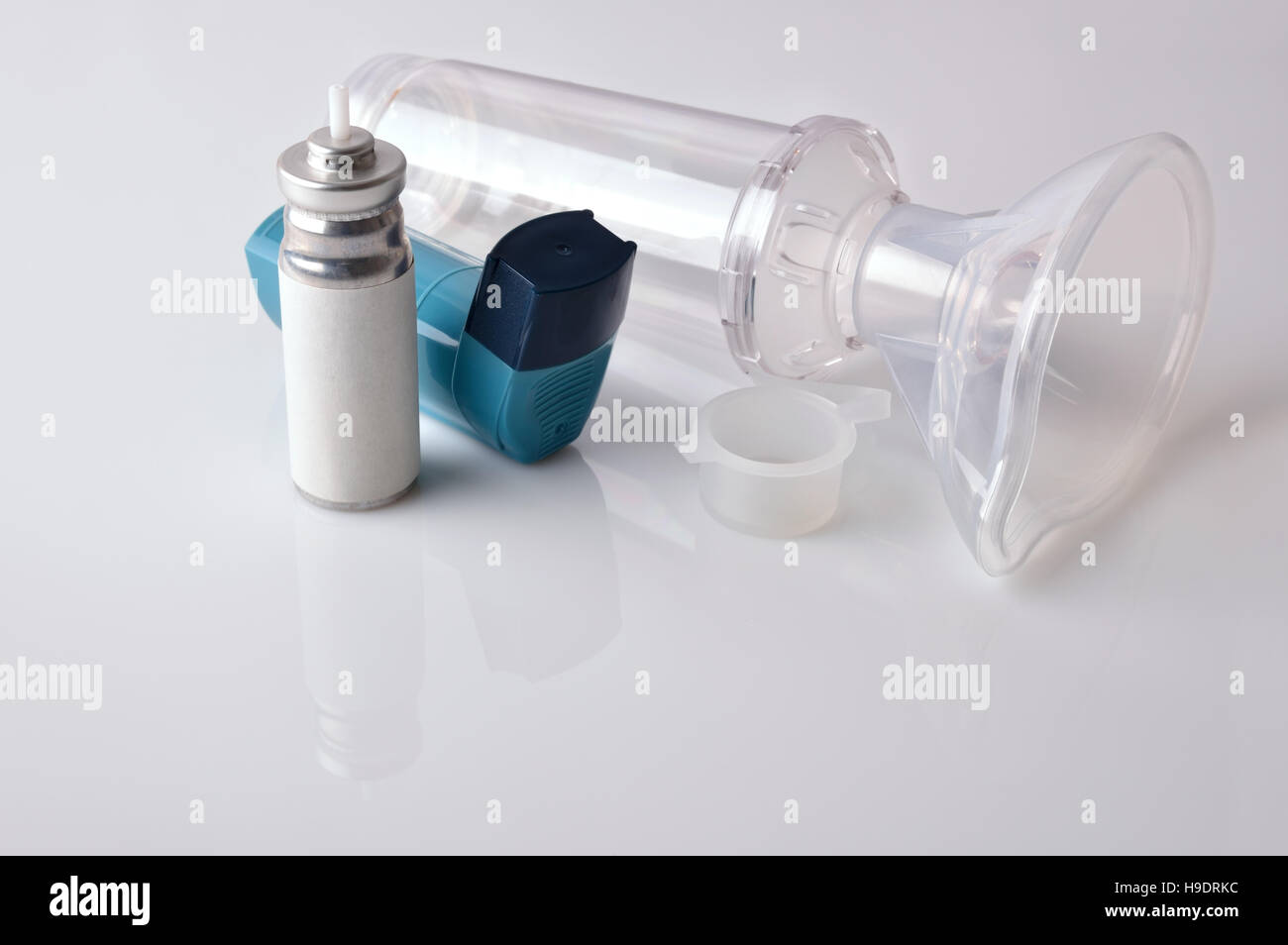 Cartridge, blue medicine inhaler, inhalation chamber and silicone mask isolated on white glass table. Elevated view. Horizontal composition Stock Photo