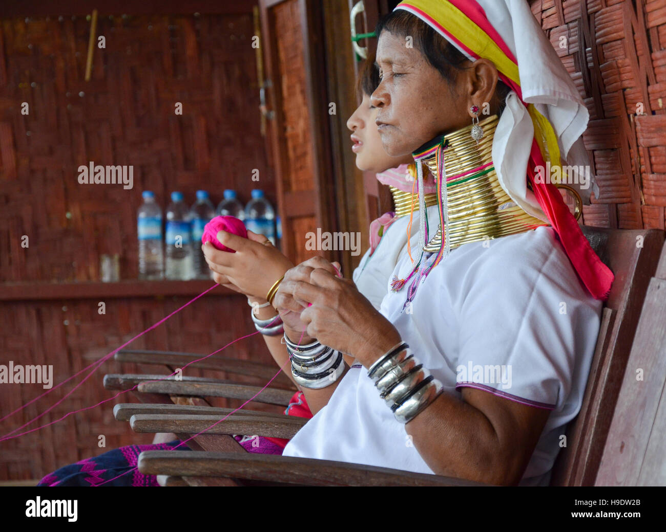 Padaung "long necked" woman, wearing the traditional metal rings around her neck, weaving on a loom Stock Photo