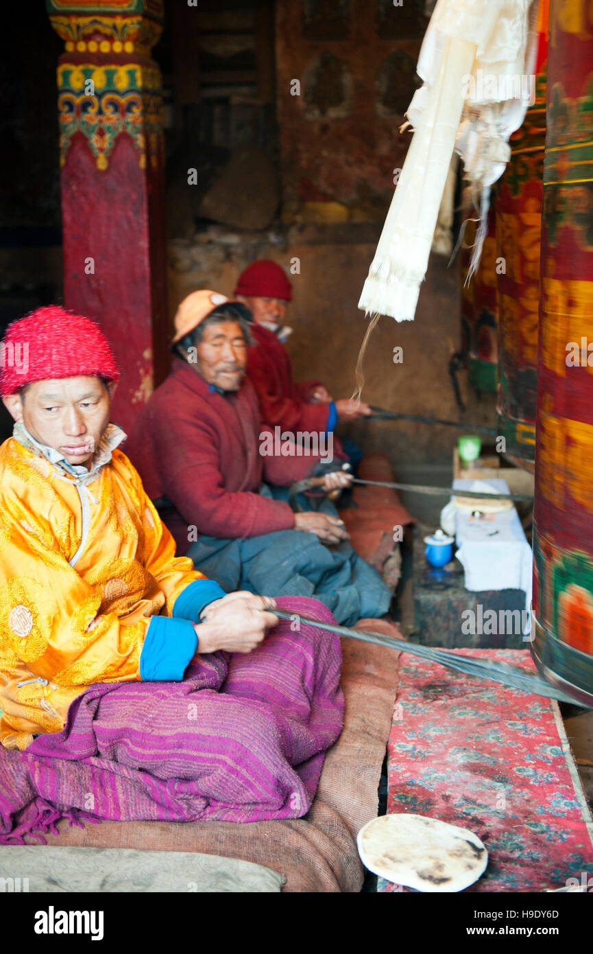 Monks at Tawang Monastery spin large prayer wheels while chanting Buddhist prayers in the remote Tawang Valley, India. Stock Photo