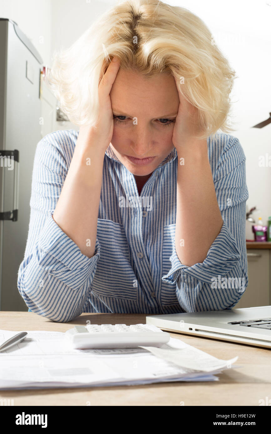 Female holding head in hands in despair whilst doing accounts Stock Photo