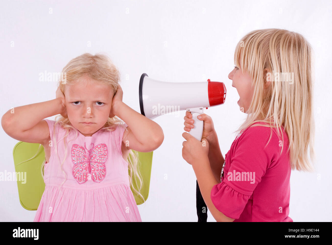 One girl screaming at another through a megaphone Stock Photo