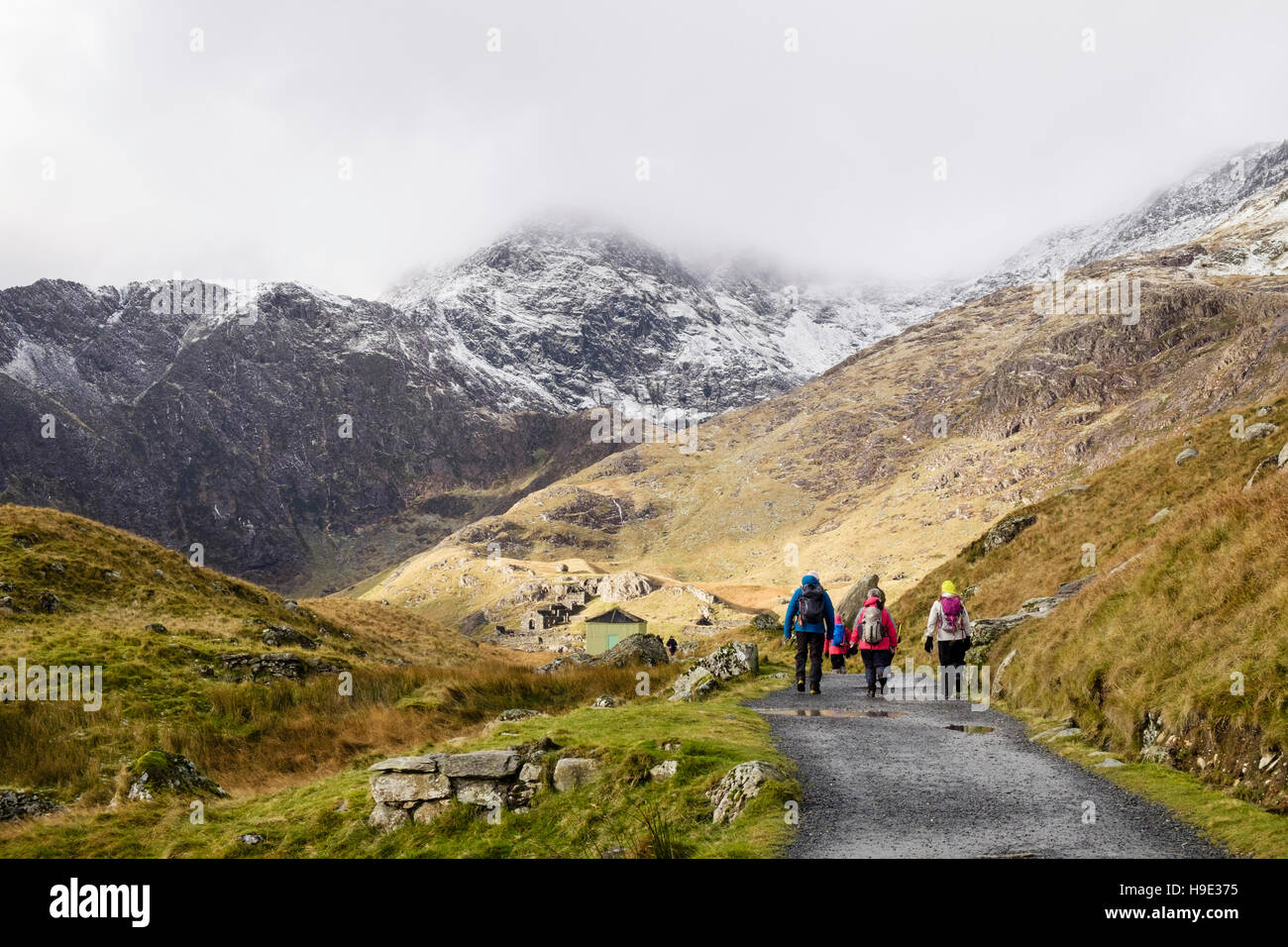 Hikers hiking on Miners' Track with snow and low cloud on Mount Snowdon in winter.  Pen-y-Pass Llanberis Gwynedd North Wales UK Britain Stock Photo