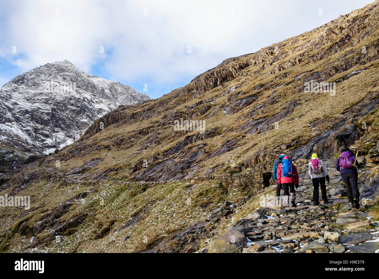 Hikers hiking to distant Mount Snowdon peak on Miners' Track with snow in winter.  Pen-y-Pass Gwynedd North Wales UK Britain Stock Photo