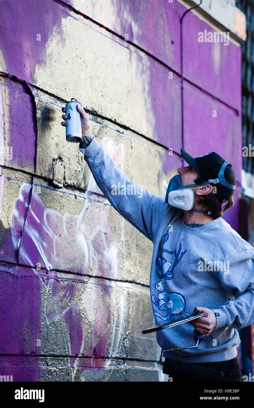 Graffiti artists work in Camden Market with spray paints and rollers