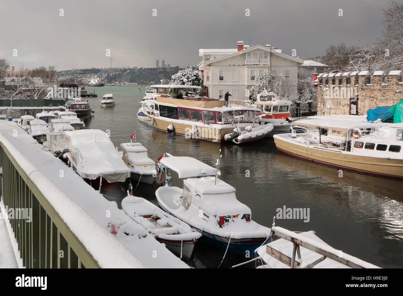 Boats and Yachts covered with snow parked on Goksu Rriver creates very nice landscape with the hill and the trees, Istanbul Stock Photo