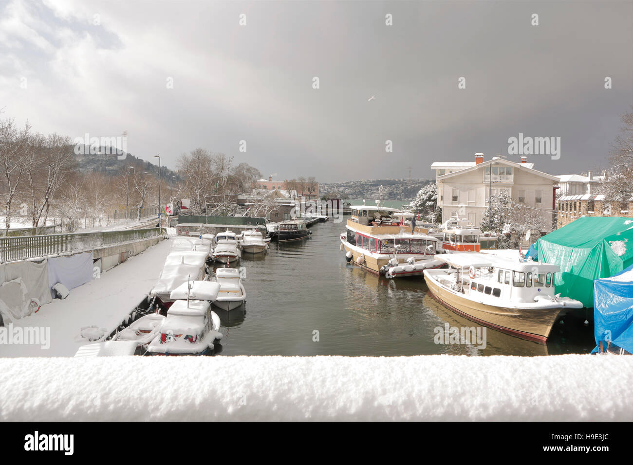 Boats and Yachts covered with snow parked on Goksu Rriver creates very nice landscape with the hill and the trees, Istanbul Stock Photo
