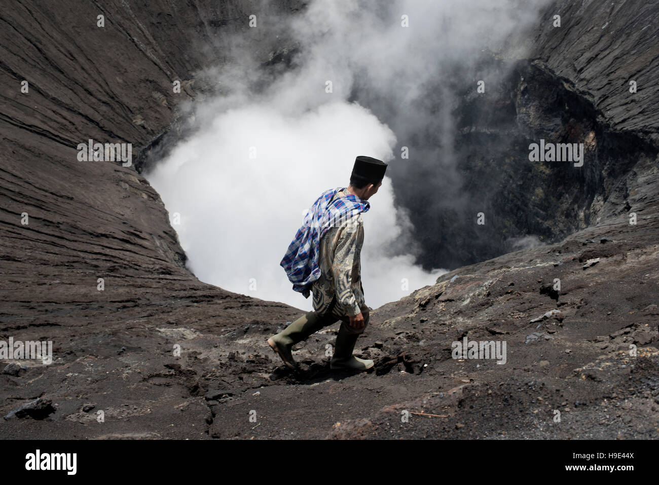 Tenggerese man walking on the edge of an active volcano in Bromo Tengger Semeru National Park. January 17, 2014 - Java, Indonesia Stock Photo