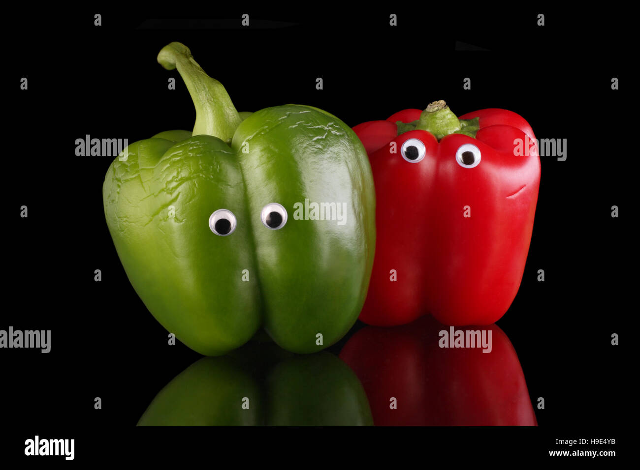 Red and green bell peppers, humourously posed as friends or partners