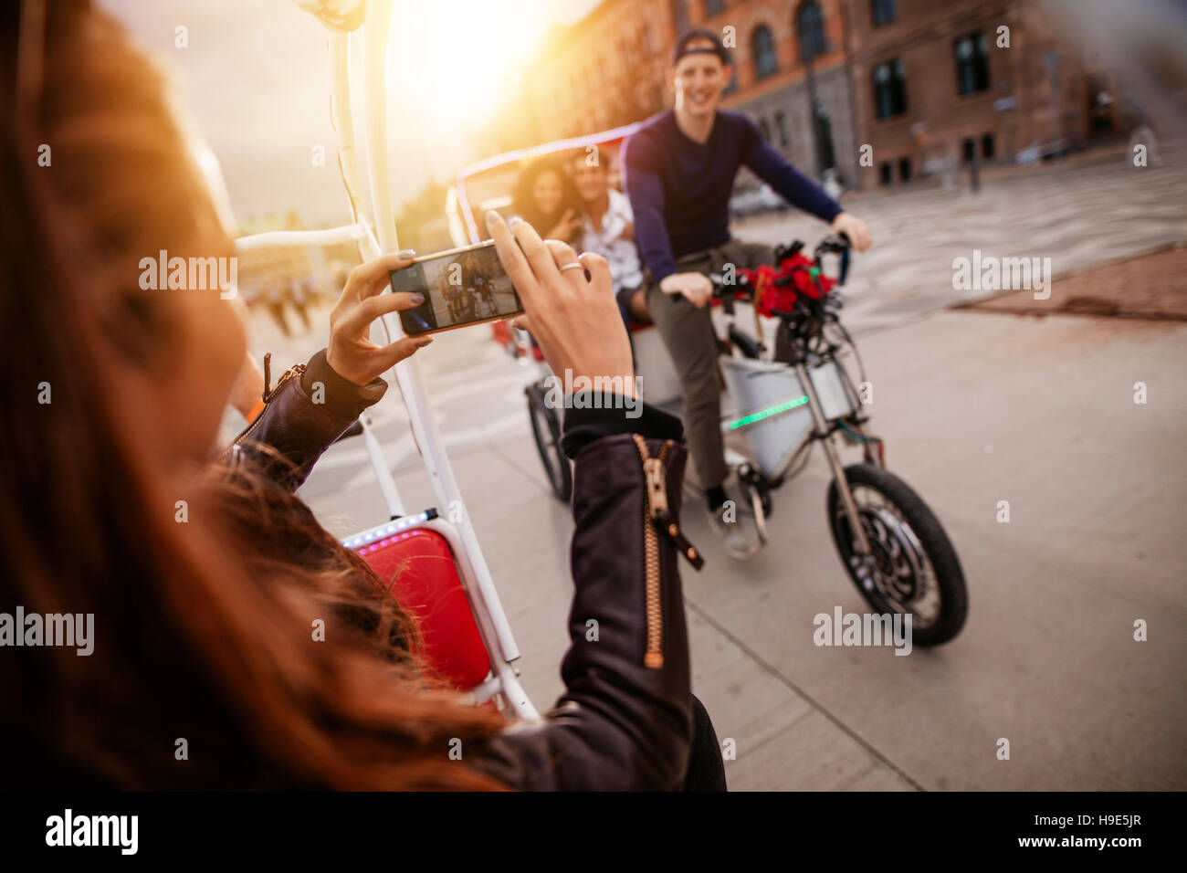 Woman taking picture of friends on tricycle ride. Friends having fun on vacation. Stock Photo