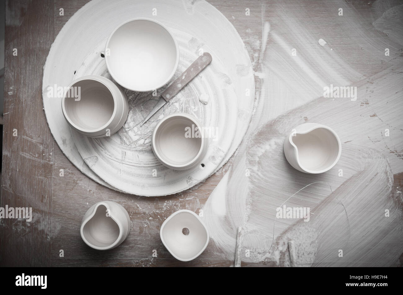 Overhead view of pottery in a ceramics on a messy work table