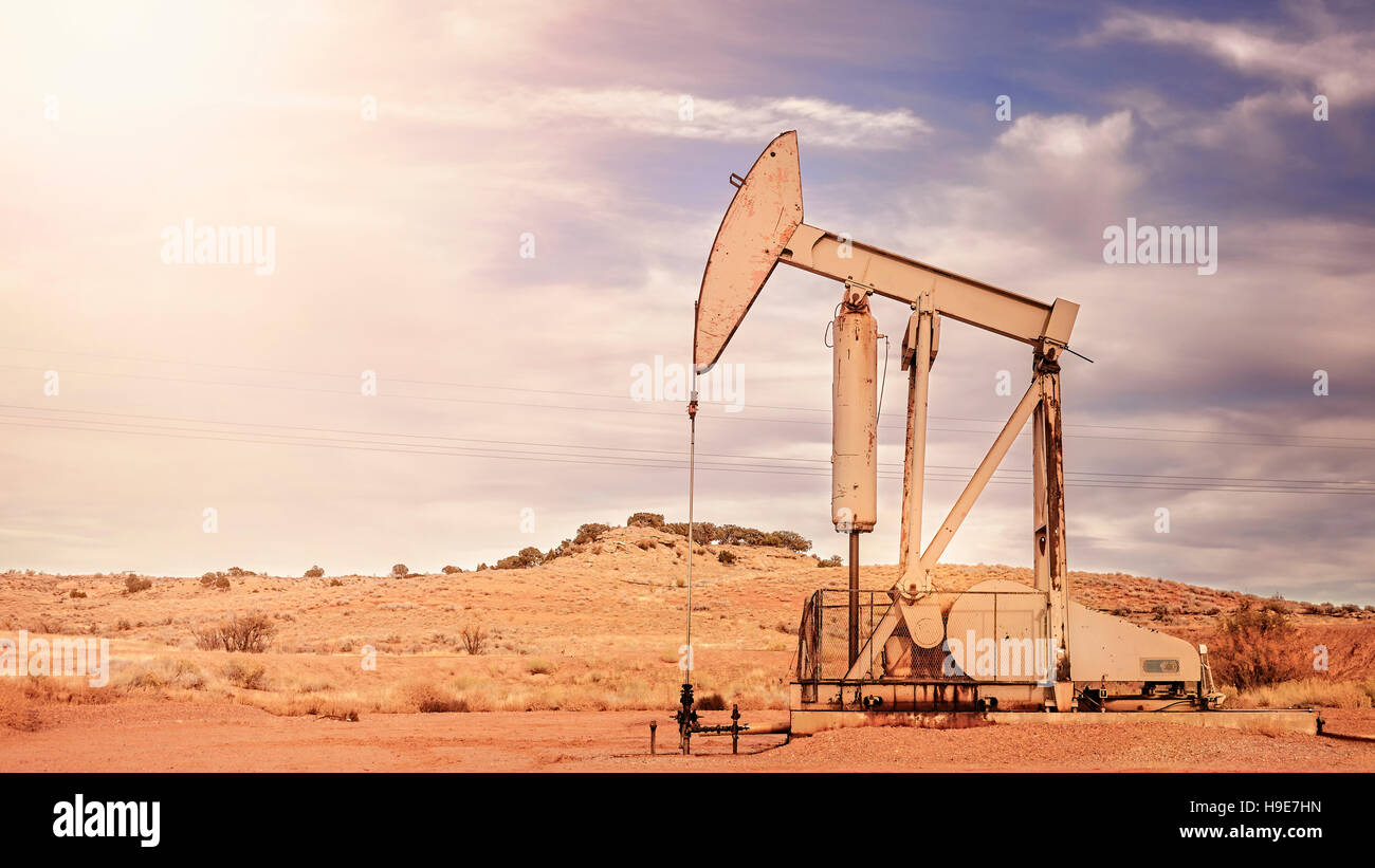 Retro toned panoramic picture of an oil pump, old industrial equipment on arid soil. Stock Photo