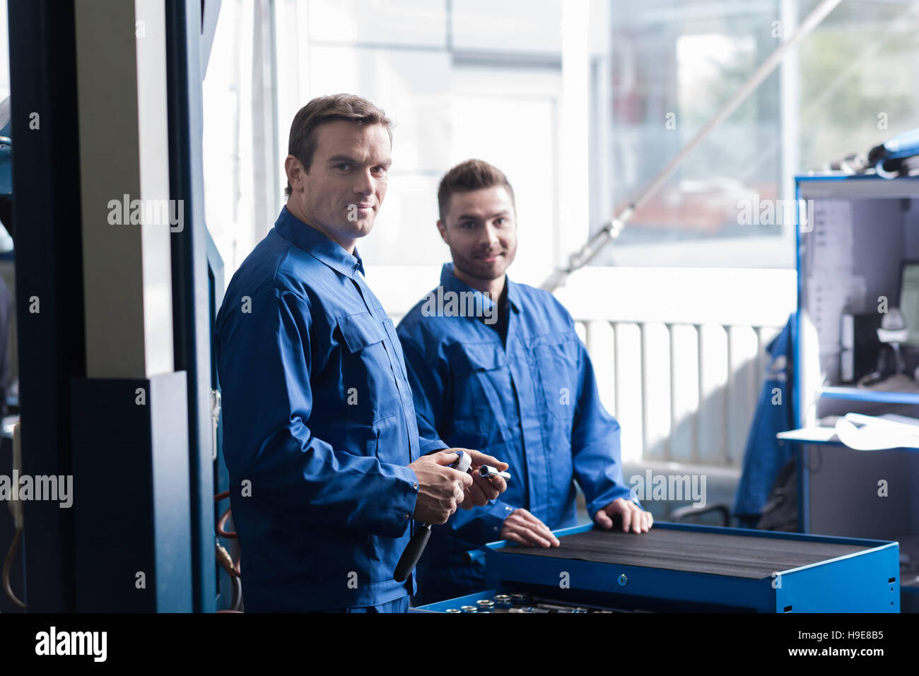 Positive mechanics standing in car service center Stock Photo