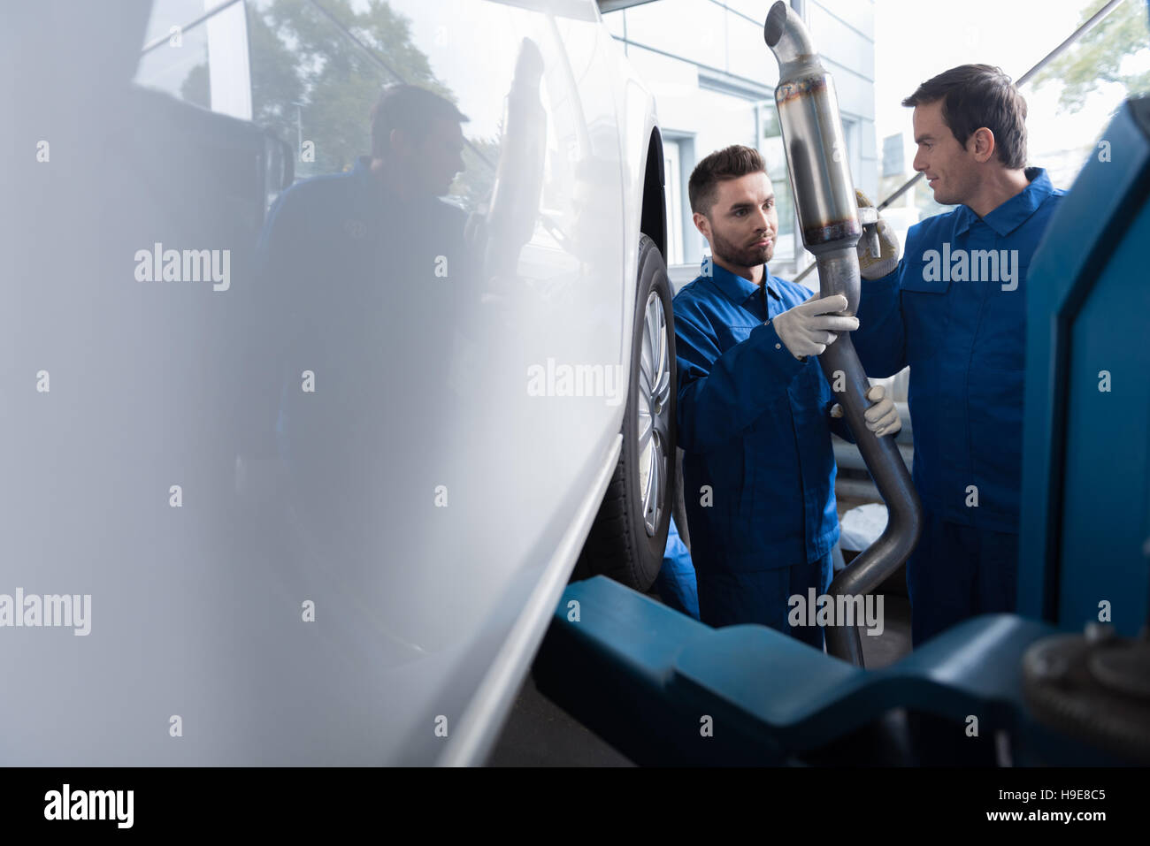 Professional car mechanics reparing muffler Stock Photo Alamy