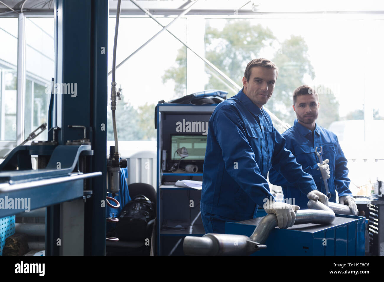 Positive car mechanics reparing muffler Stock Photo Alamy