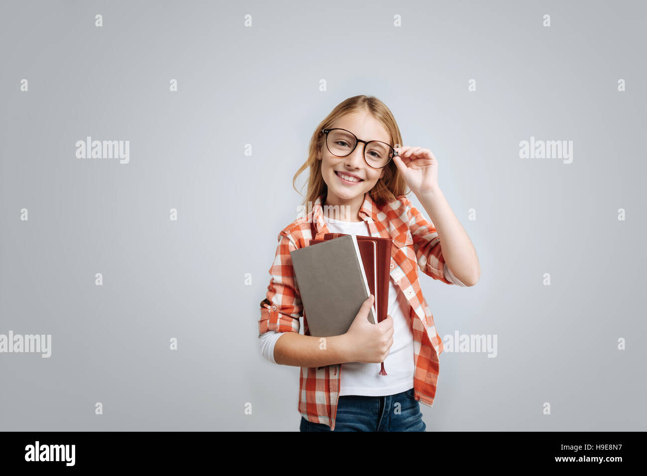 Positive little girl holding books Stock Photo - Alamy