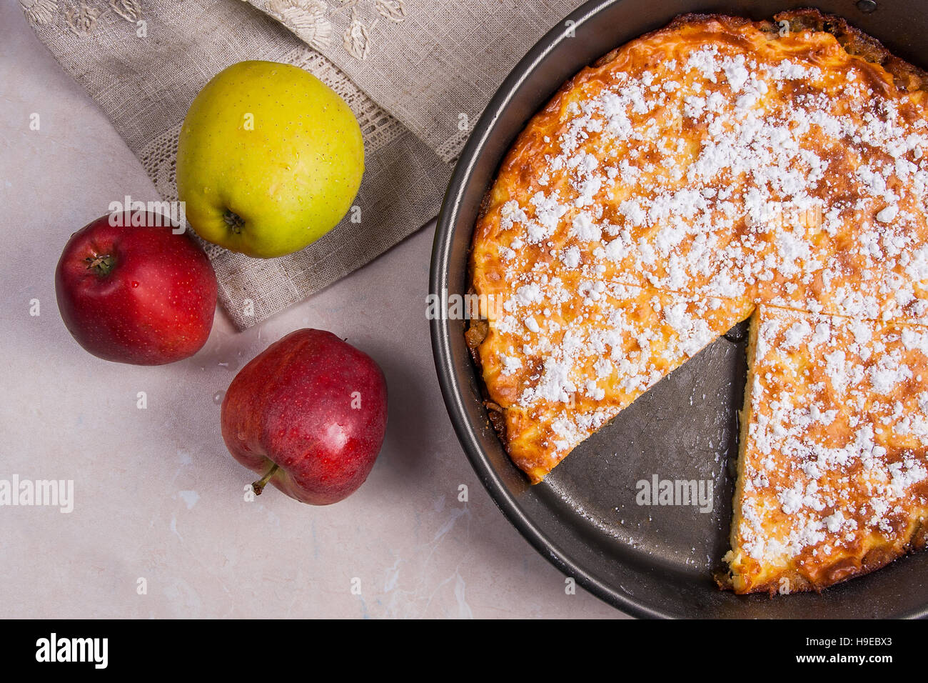 Homemade freshly baked apple pie with apples. Dessert ready to eat. Several organic red and green apples in the background. Stock Photo
