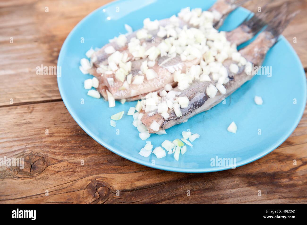 Traditional Dutch raw herring with onions on plate on wooden background Stock Photo