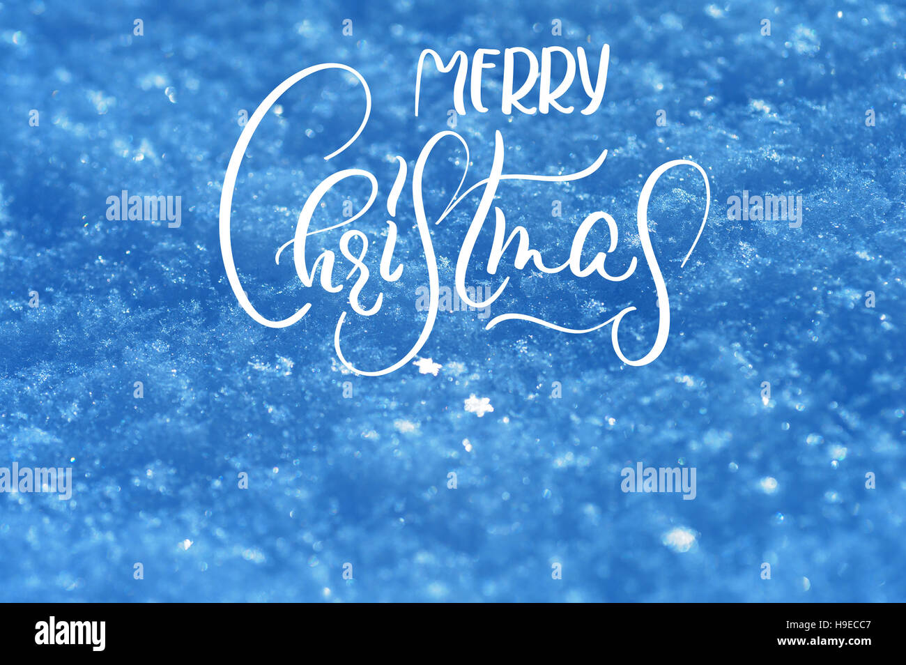 texture of snow in blue tones background with text Merry Christmas. Calligraphy and lettering Stock Photo