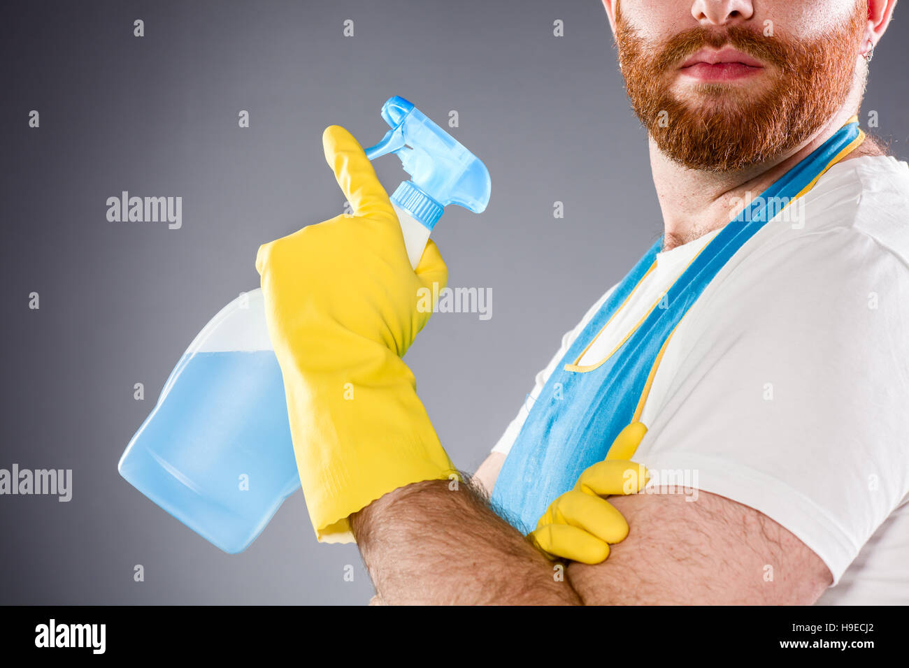 Cleaner Man Holding a Detergent Wearing an Apron and Plastic Gloves Stock Photo