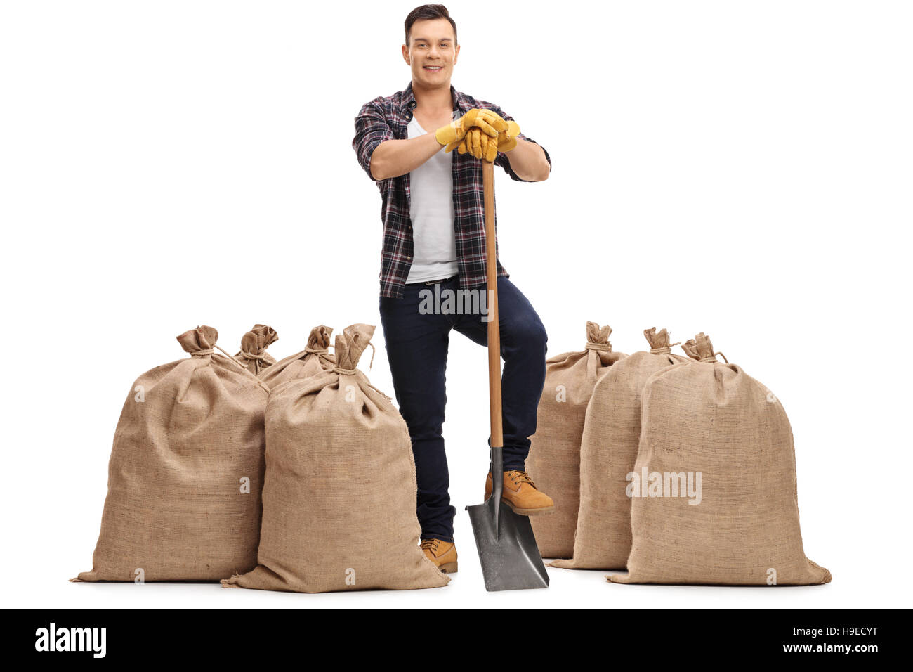 Full length portrait of a joyful farmer with a shovel standing between ...