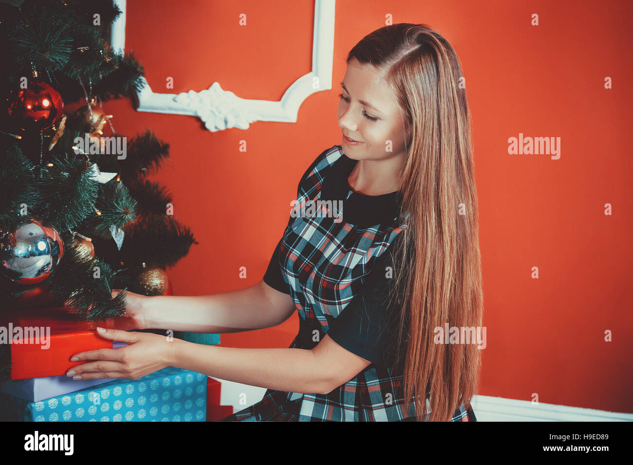 beautiful portrait of young mother puts the gifts under the Christmas tree in new year room. The idea for postcards. Soft focus. Shallow dof Stock Photo