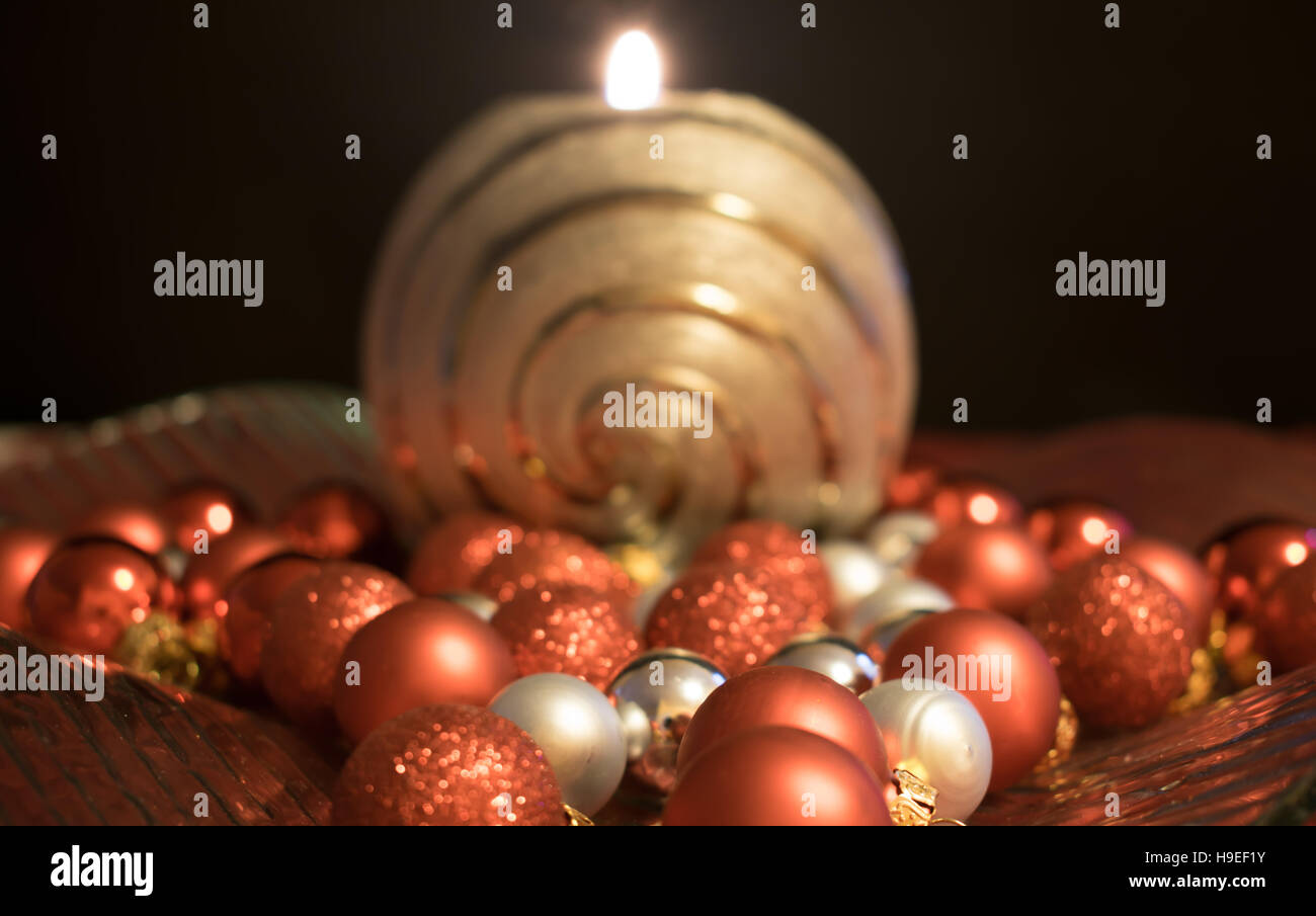 A silver burning candle in a decorative bowl decorated with Christmas balls. Stock Photo