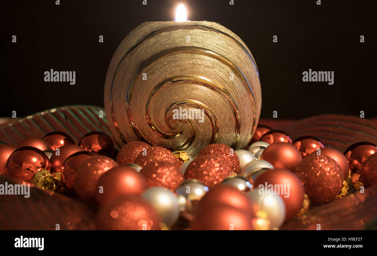 A silver burning candle in a decorative bowl decorated with Christmas balls. Stock Photo