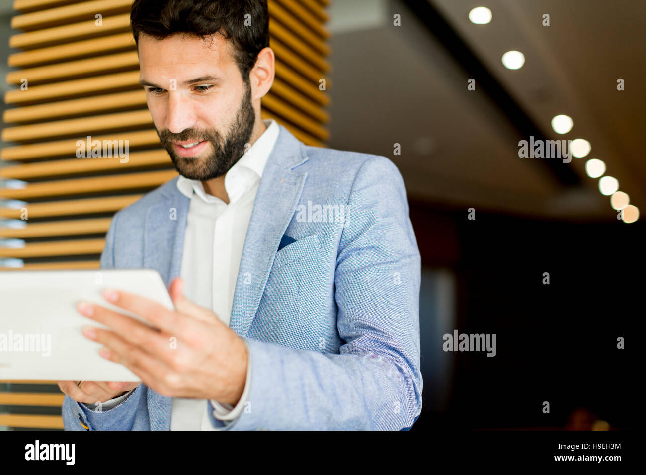 Smiling young businessman using his digital tablet at the office Stock ...