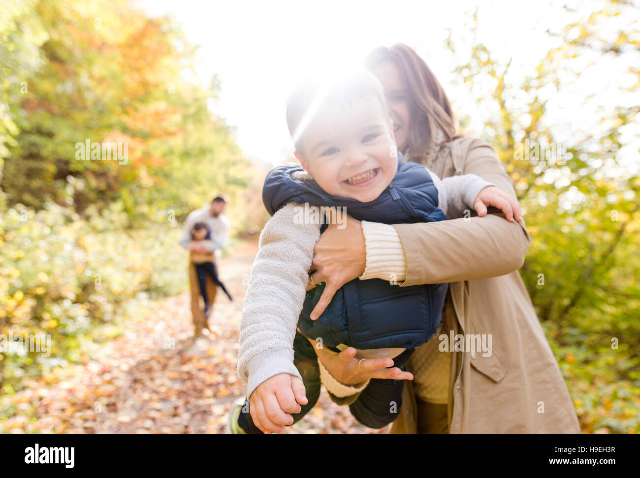 Beautiful young family on a walk in autumn forest Stock Photo - Alamy