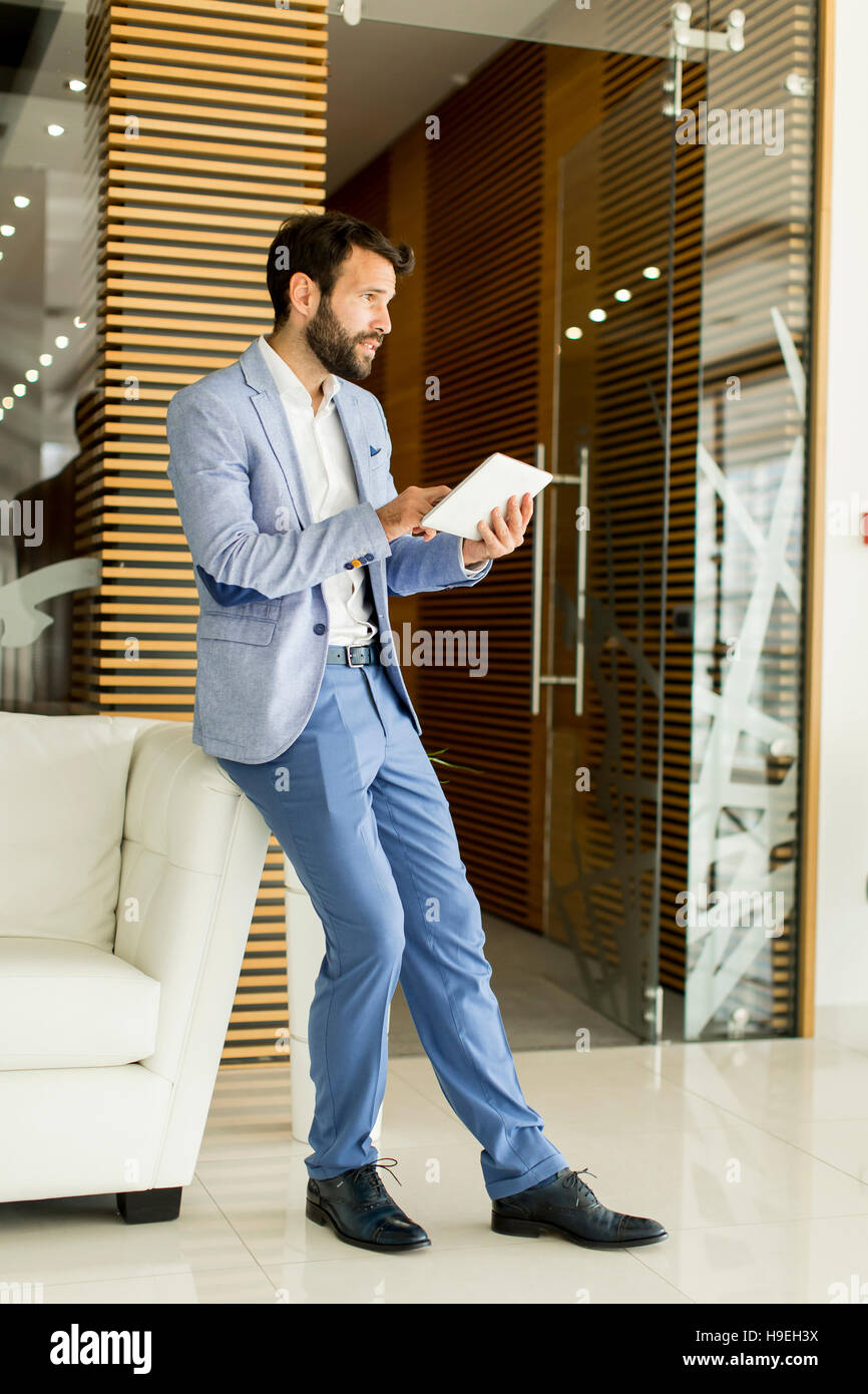 Smiling young businessman using his digital tablet at the office Stock ...