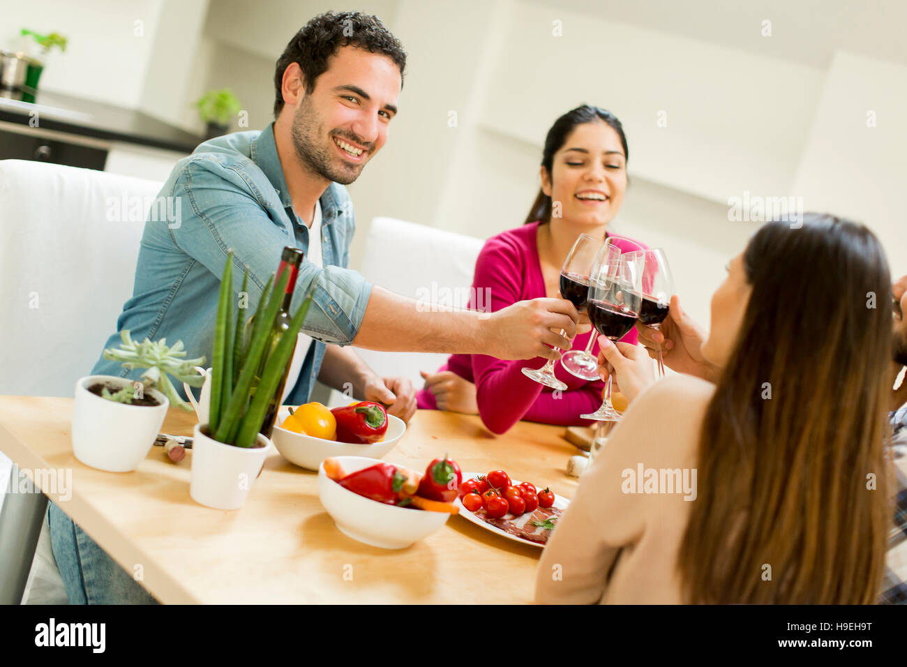 Group of happ young people sitting by the table eating and drinking red wine Stock Photo Alamy